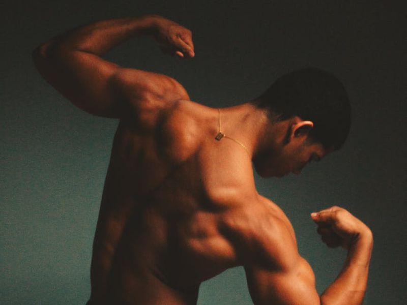 Man holding a difficult static pose, showing muscle definition and stability.