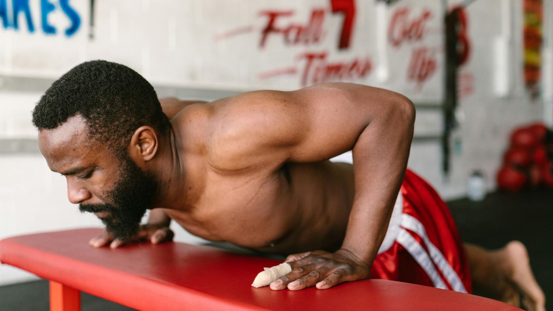 Man performing a controlled bodyweight exercise in a minimalist gym setting.